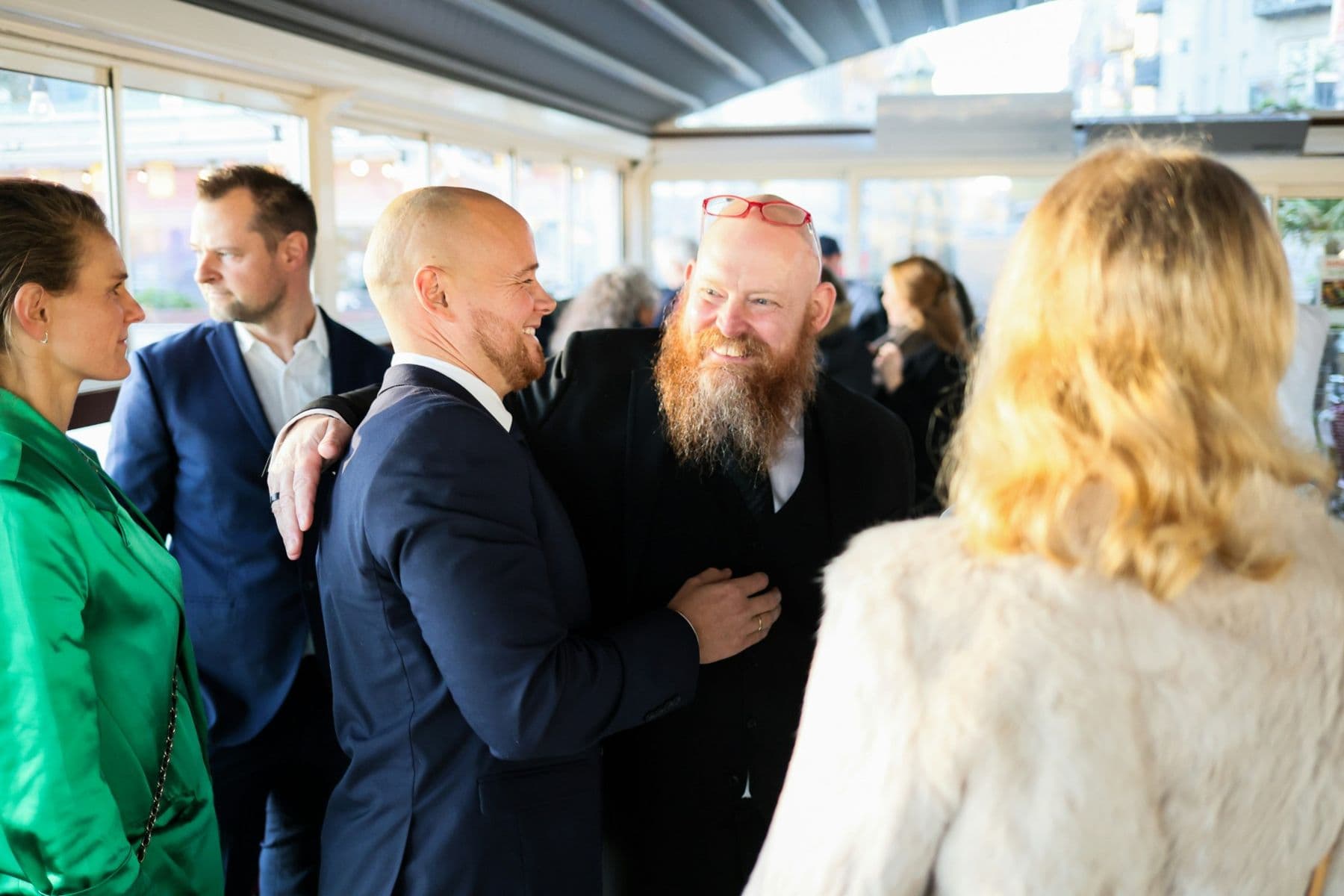 Smiling colleagues greeting each other at a company cocktail.